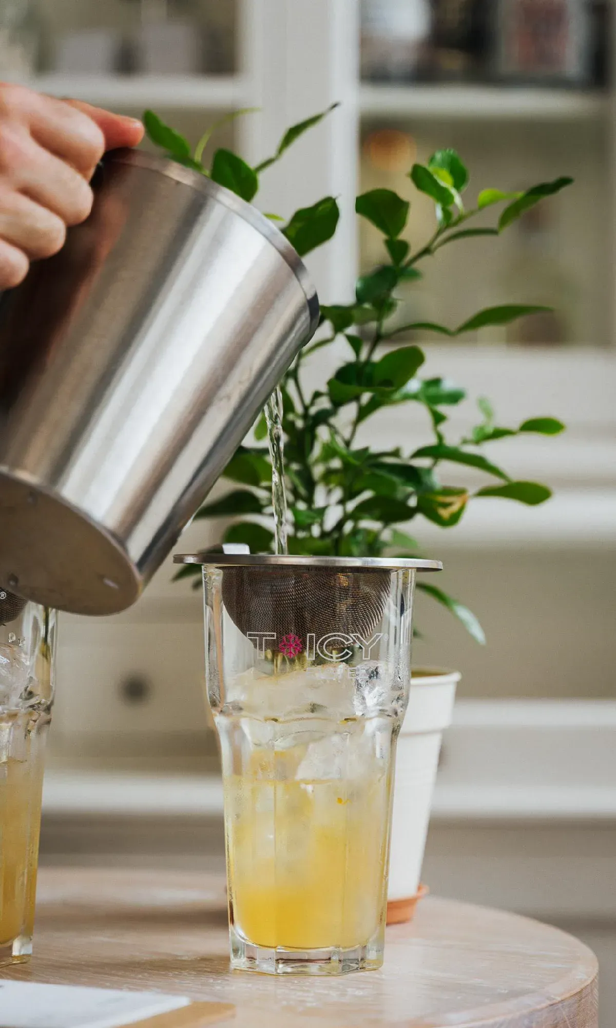 Selbstgemachte, eisgekühlte Limonade wird durch ein Sieb frisch in ein hohes Glas gegossen.